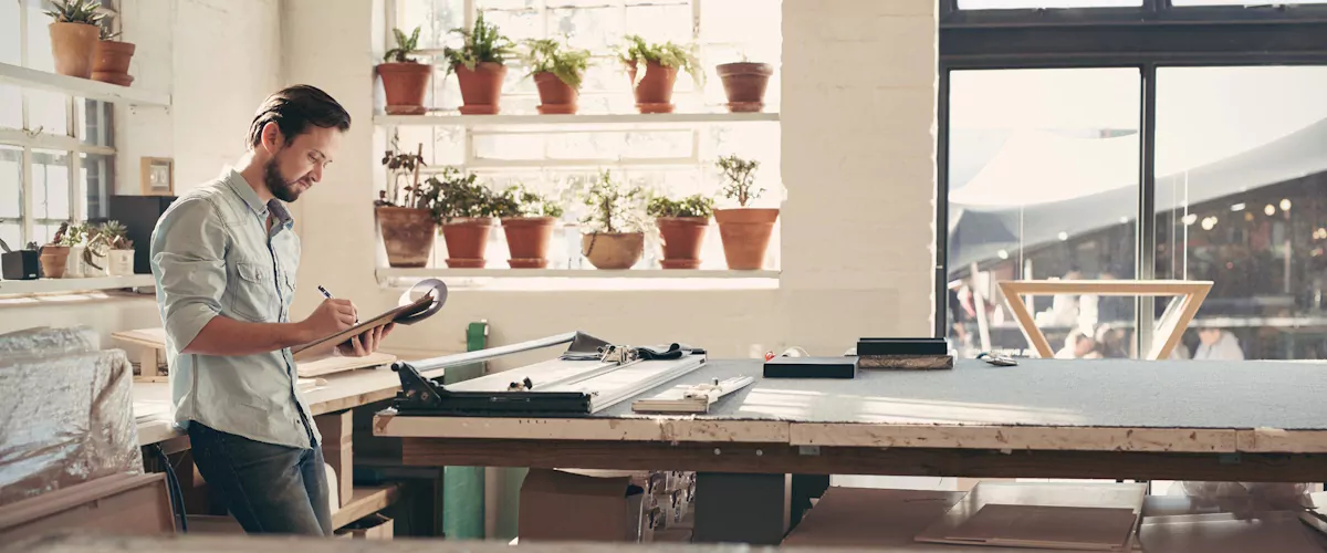 Selbstständiger prüft Unterlagen am Arbeitsplatz zur Planung von Anspruch auf Arbeitslosengeld bei selbstständiger Tätigkeit