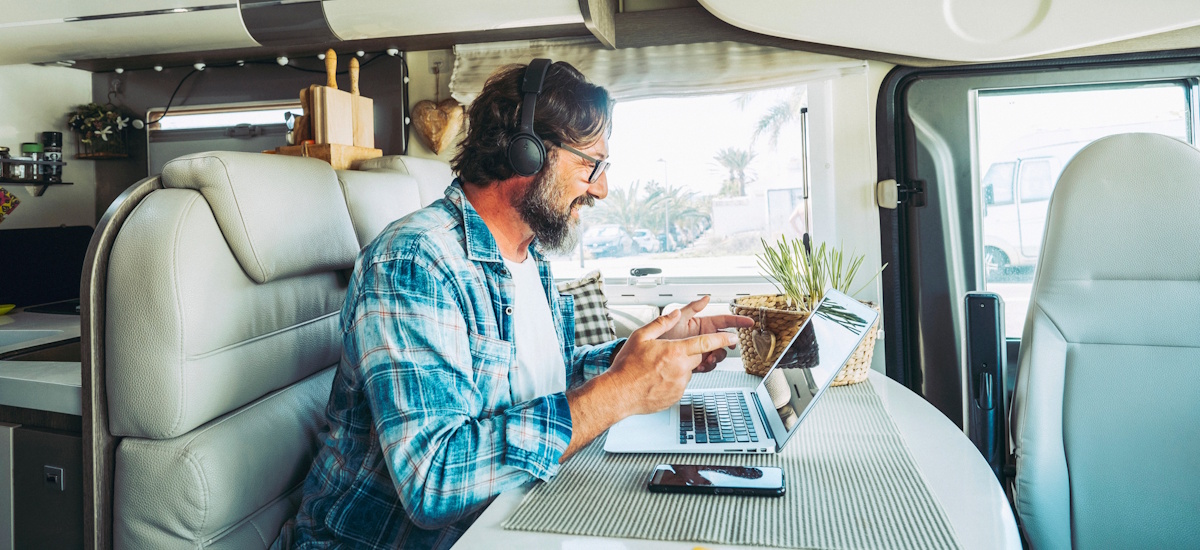 Mann arbeitet ortsunabhängig mit Laptop im Wohnmobil und führt ein Online-Meeting – Beispiel für unabhängige Arbeit und digitales Arbeiten von unterwegs.