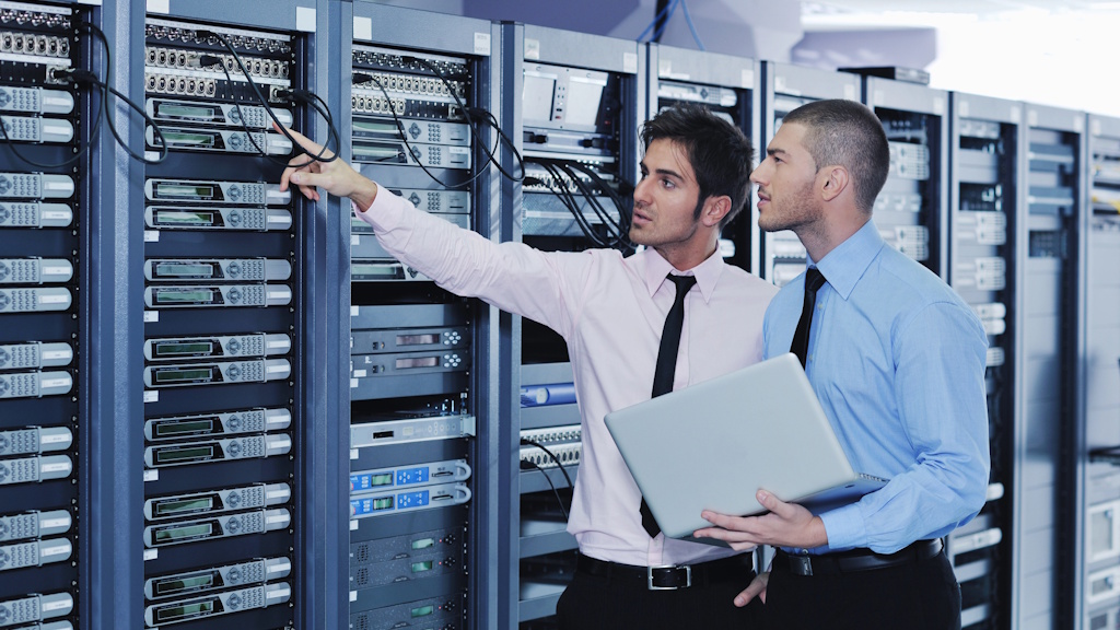 Zwei IT-Experten prüfen Server-Racks in einem Cloud-GPU-Rechenzentrum für skalierbare KI-Infrastruktur.