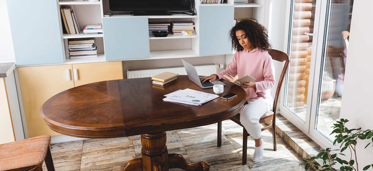 Selbstständige arbeitet im Homeoffice und prüft Unterlagen, um ihr Arbeitszimmer abzusetzen.